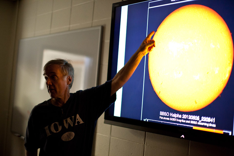 A man points at a projector showing the Venus transit over the sun.