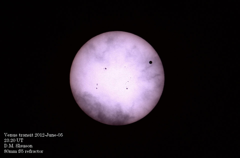 Telescope view of the sun with a tiny dot, Venus, in the upper left quadrant.