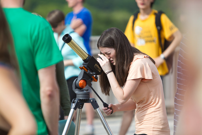 A girl looks into a telescope.