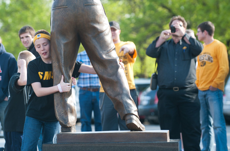 young fan wrestles with statue