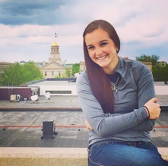 student posing on campus with old capitol museum in background