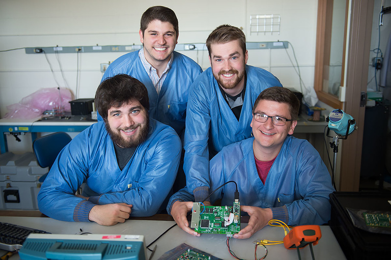 Bryan Senchuk, Kevin Klosterman (top), Tyler Dunkel, and Patrick Maloney (bottom) show off the circuit board and microprocessor they built to reenact Van Allen&#039;s experiment.