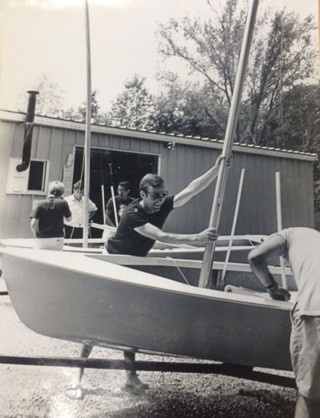 Black and white photo of men adjusting mast on sailboat