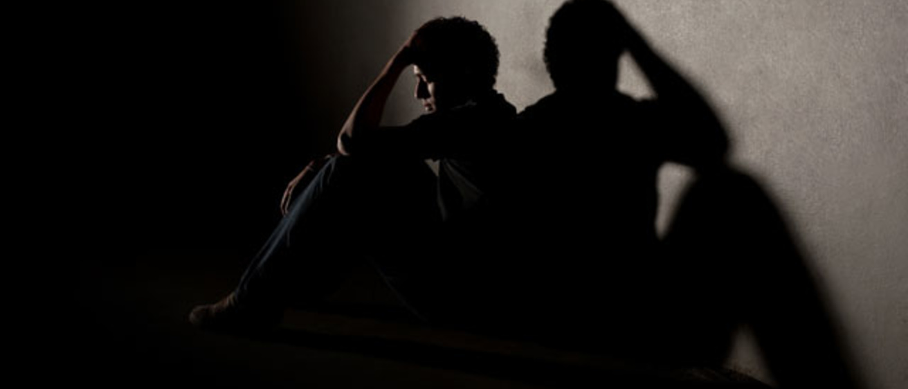 young man sitting in shadowy room