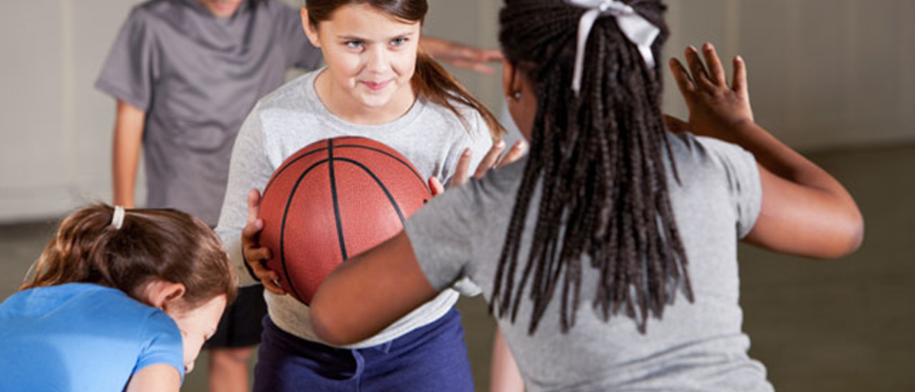 elementary aged children in gym class playing basketball