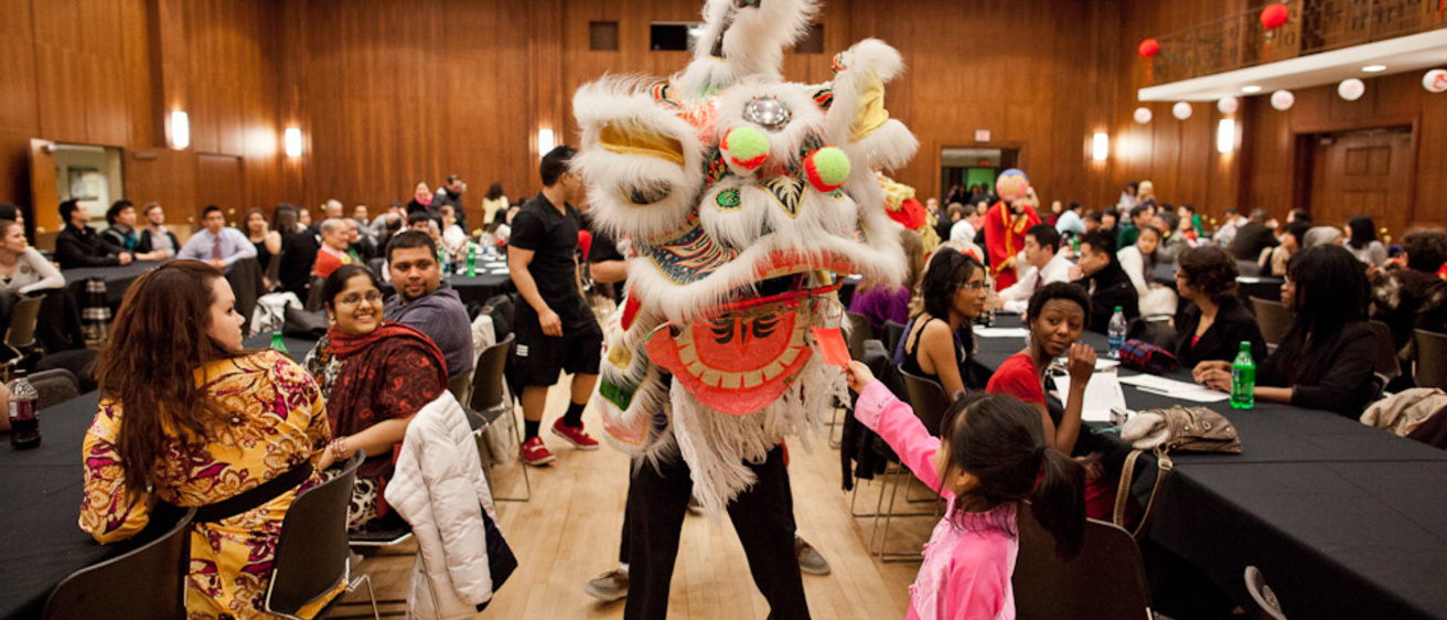 A young girl feeds a donation card to a man dressed in a traditional Vietnamese dragon costume at the IMU Main Ball Room in Iowa City.