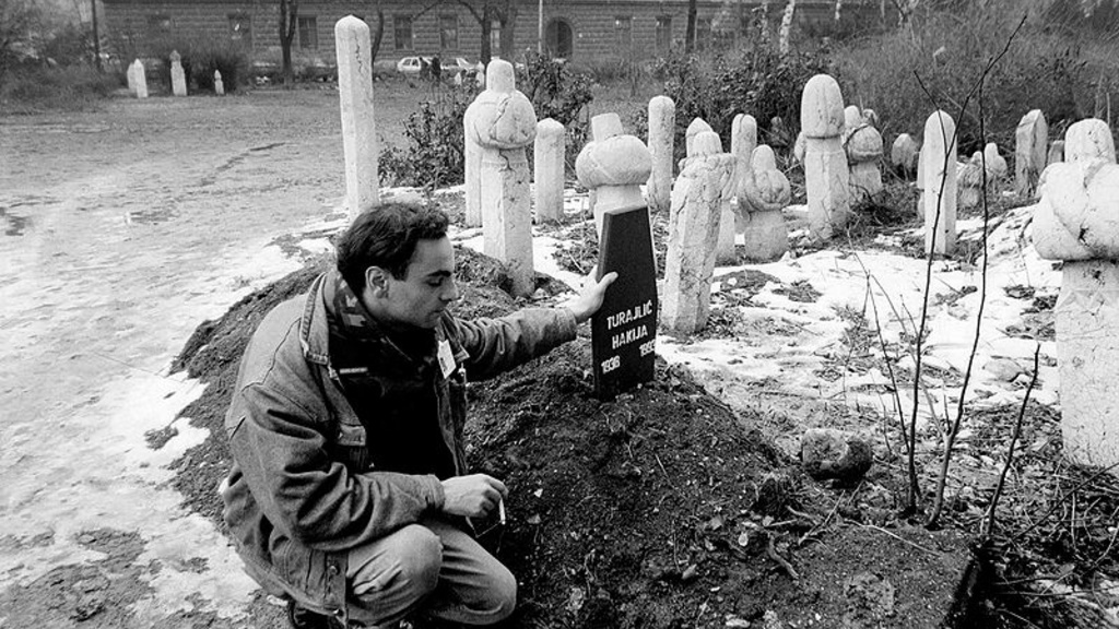 Man kneels by grave stones.