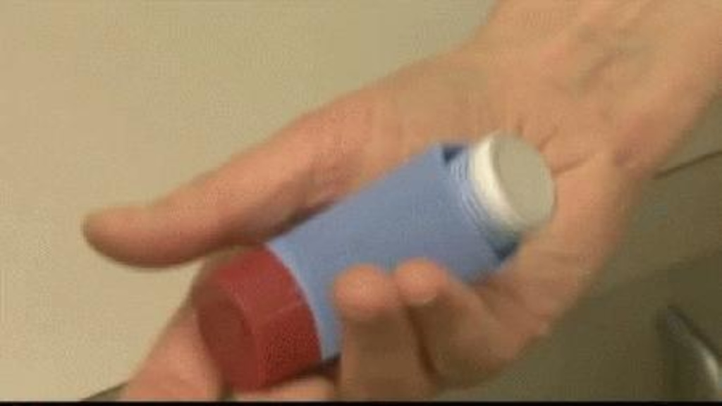 Close up photo of a hand holding an inhaler for asthma treatment