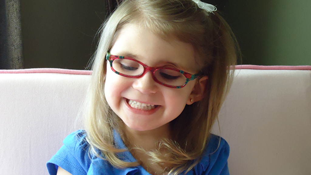 young girl wearing red glasses, smiling