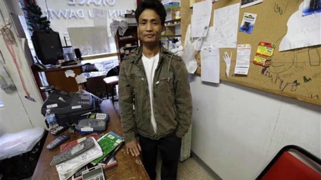 Ngun Za Bik stands at the front counter of his Grace Chin Store that once housed a pizza restaurant, in Columbus Junction, Iowa, on Wednesday, April 17, 2013.  AP Photo by Charlie Neibergall