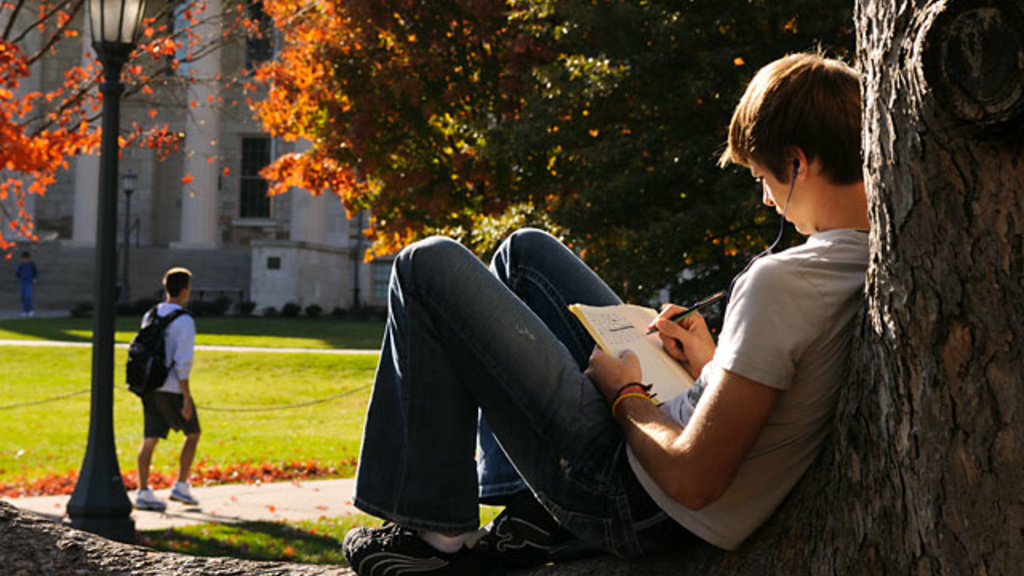Male student studying on the Pentracrest on a fall afternoon