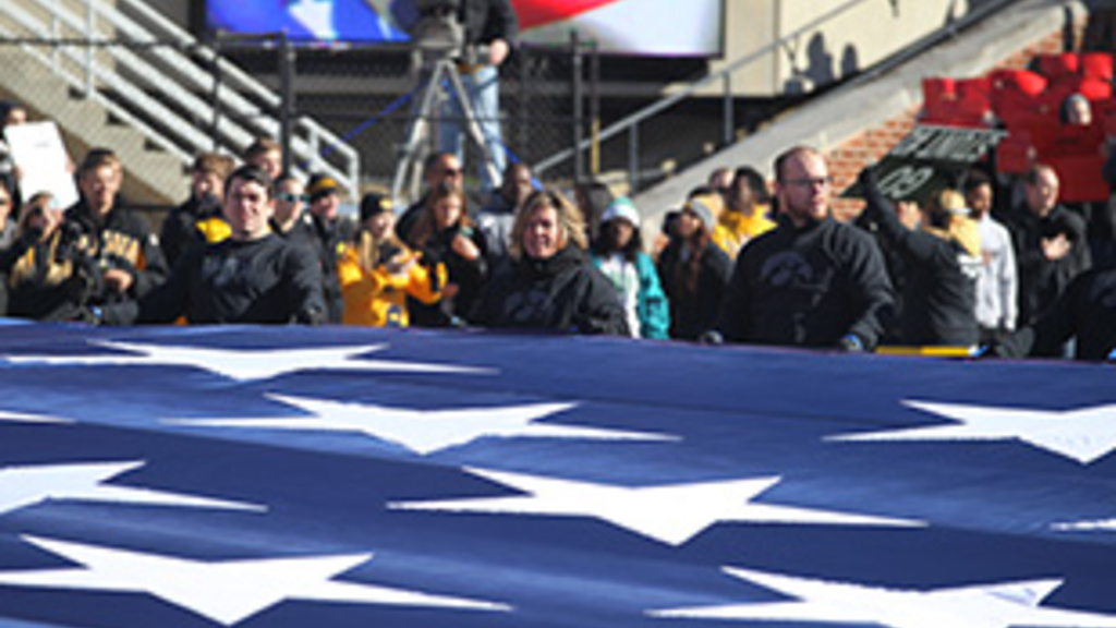UI distance education student veteran helps carry U.S. flag at Kinnick during pregame activities.