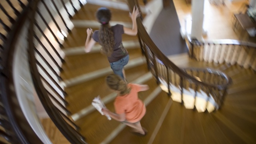 Two girls running up a spiral staircase at a museum