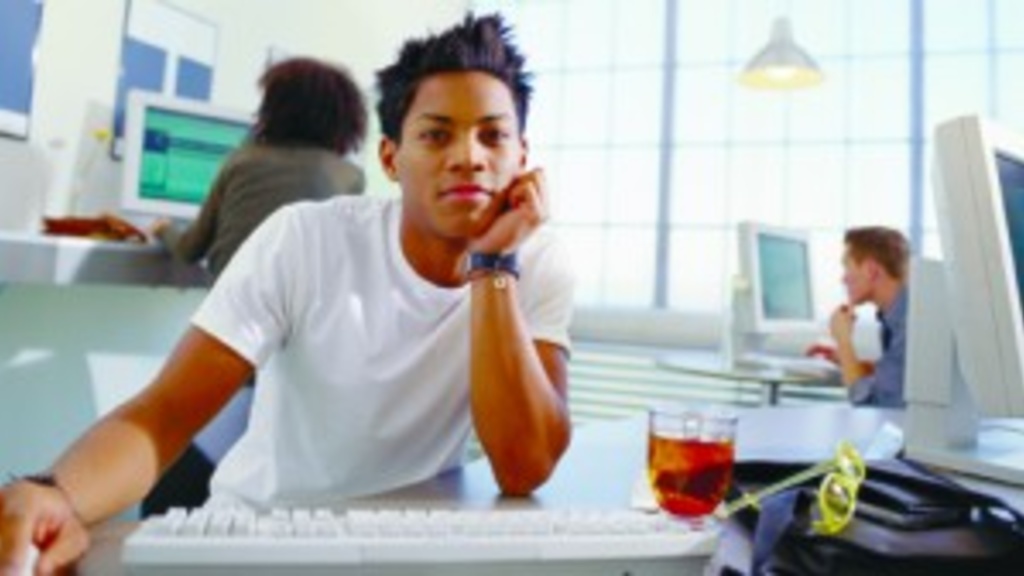 A young man sits in front of a computer keyboard