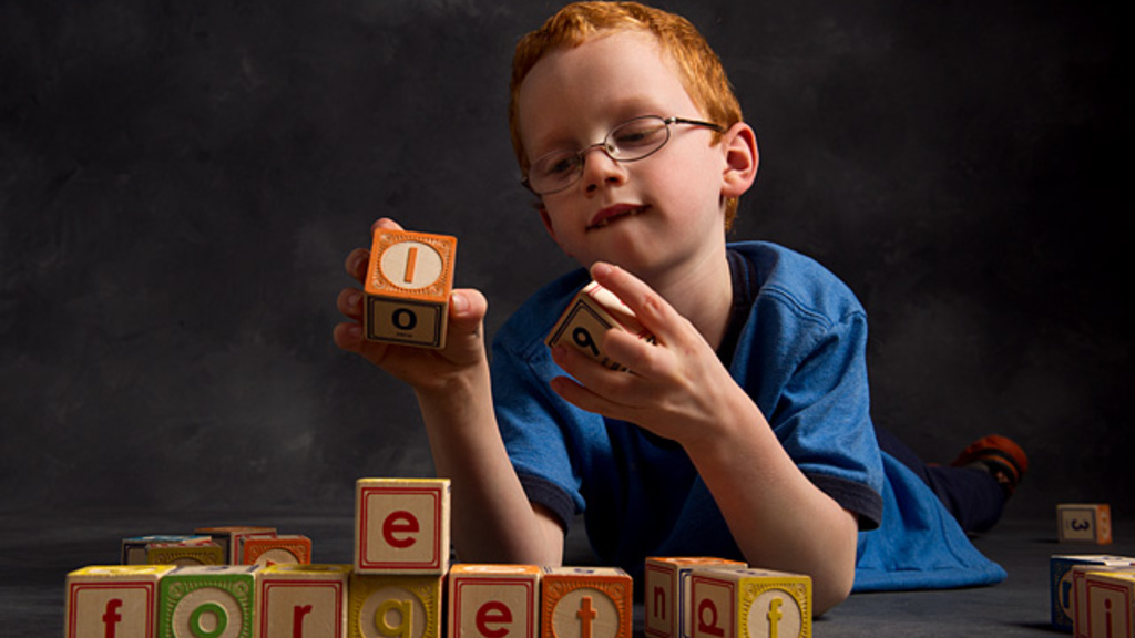 A boy makes words out of letter blocks