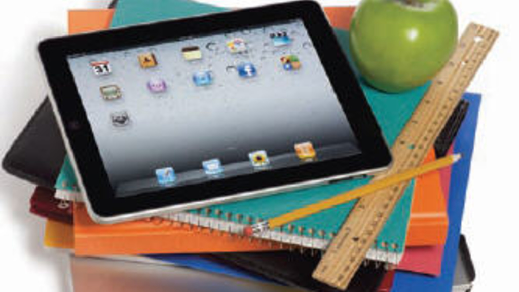 iPad on a stack of notebooks with apple and ruler