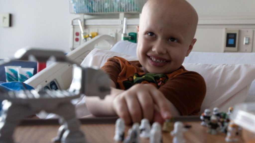 Seven-year-old Jacon Flesher of Manchester who spent his cancer remission collecting toys for other young oncology patients, plays a game while in bed