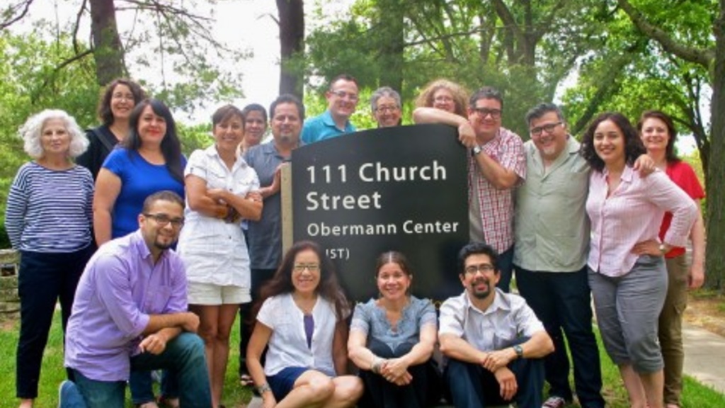 A group photo of Latino scholars around the Obermann Center signage outside of the building