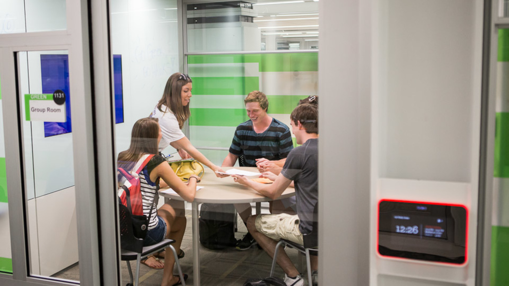 A group of college students talk around a table inside a private room