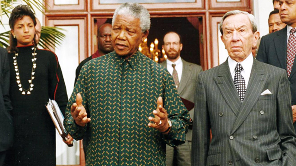 Susan Rice, Nelson Mandela, and Secretary of State Warren Christopher emerge from a meeting after negotiations witih Ron McMullen in the background.