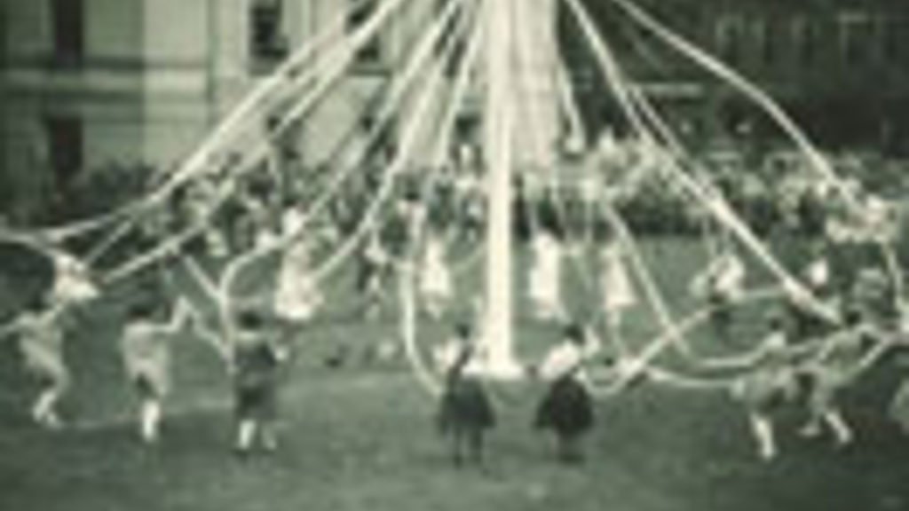 Women in costume dancing with a maypole on the Pentacrest lawn