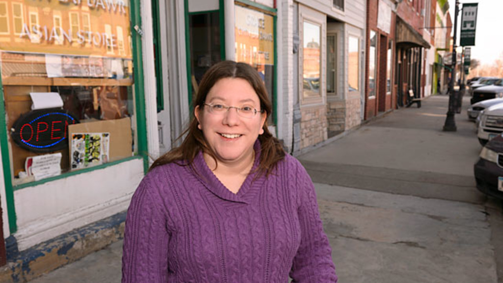Cristina "Nina" Ortiz poses in front of the Grace Chin Store, a Burmese owned grocery store on Main Street in Columbus Junction.