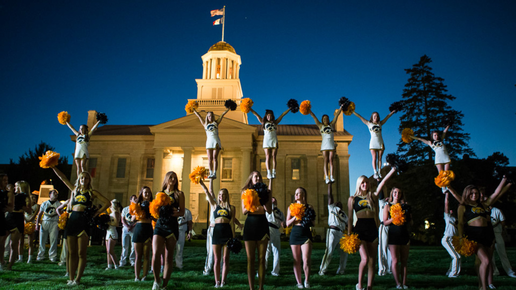 A group of male and female cheerleaders performing in front of a building