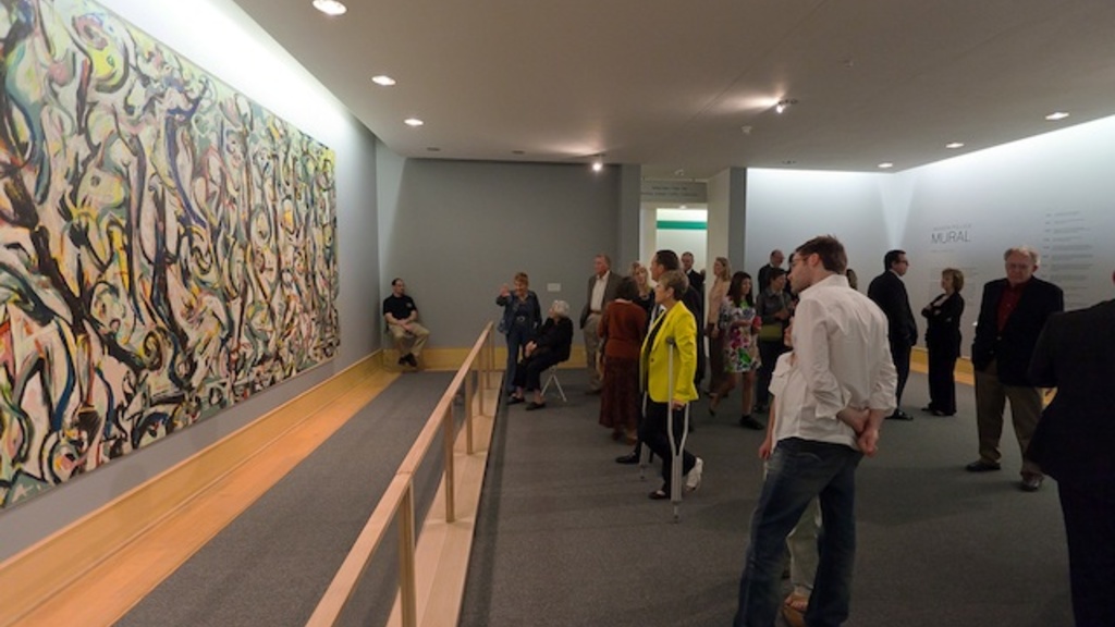 Several people looking at a large painting