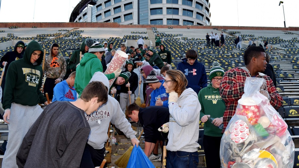 students cleaning up football stadium seats
