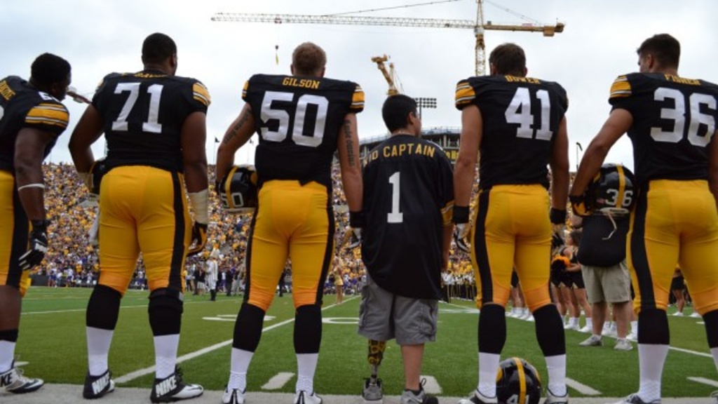 Kid captain standing with UI Hawkeye football players