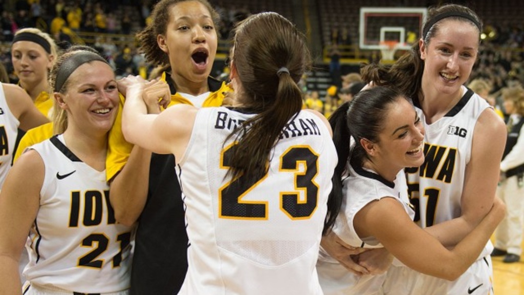 Members of the women's basketball team jump and hug on the court after a victory.