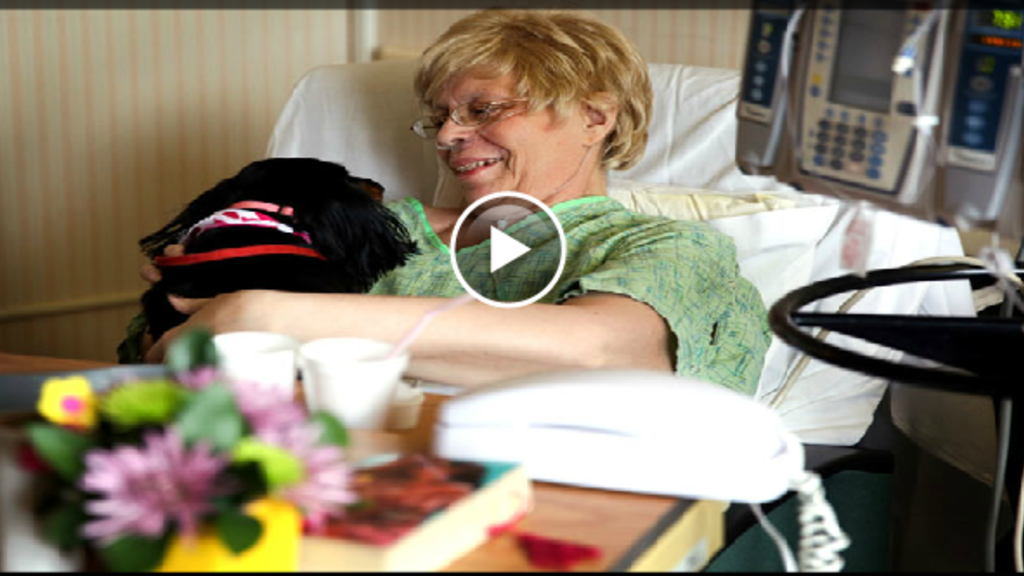 A woman cuddles a dog while a patient in a hospital 