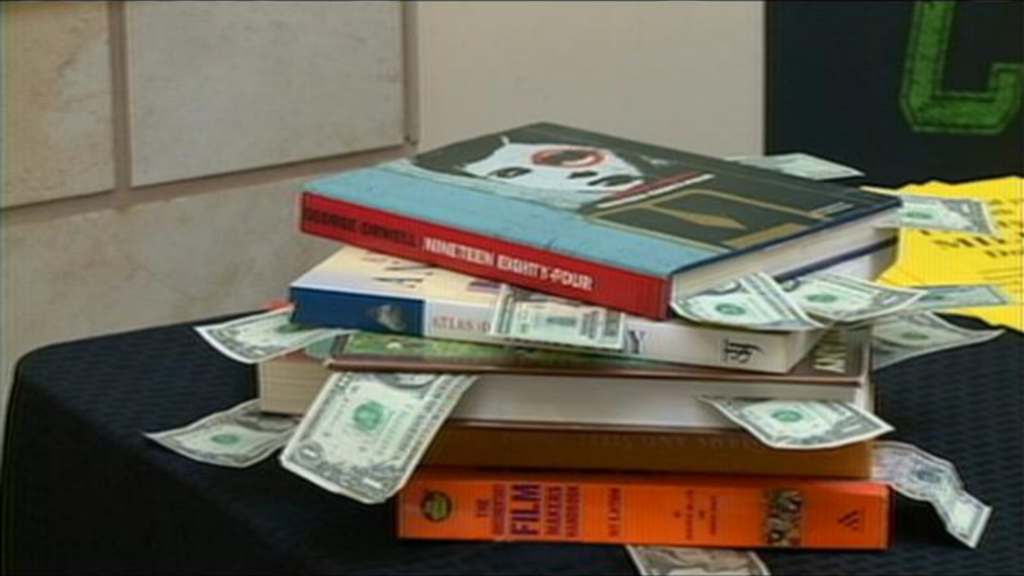stack of books with dollar bills sticking out from the pages