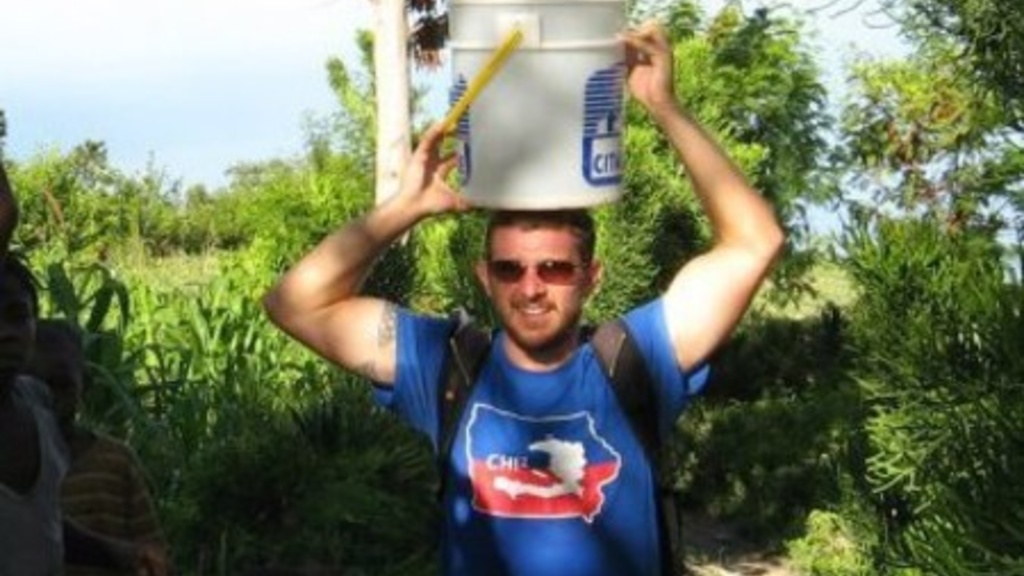UI alumnus Shaun Harty balances a pail on his head while delivering healthcare in Haiti