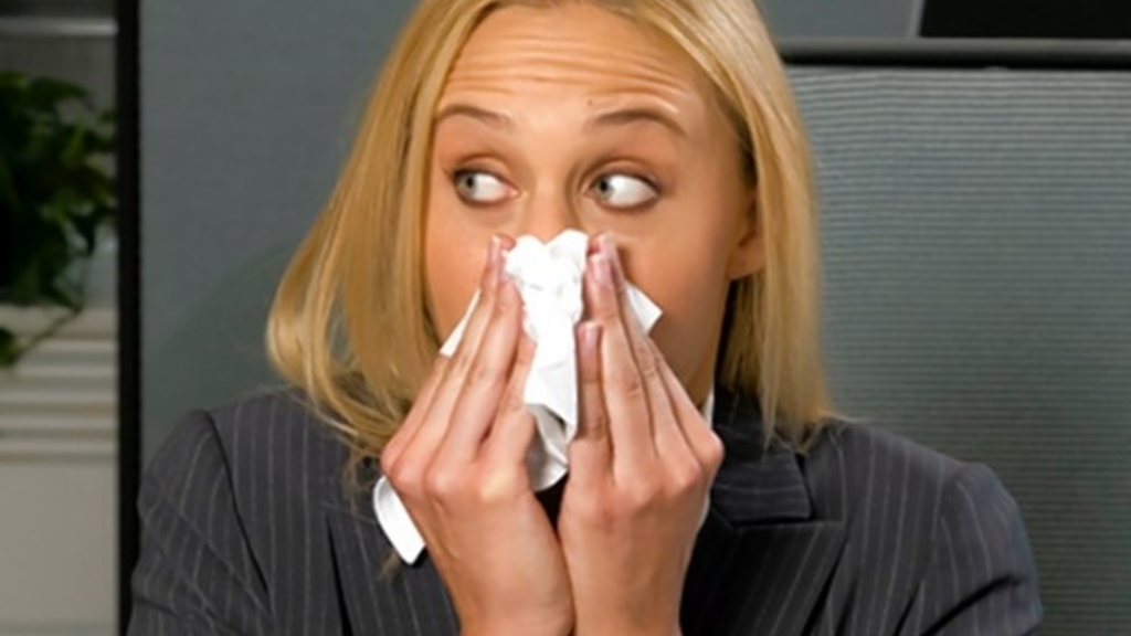 A woman blows her nose into a Kleenex