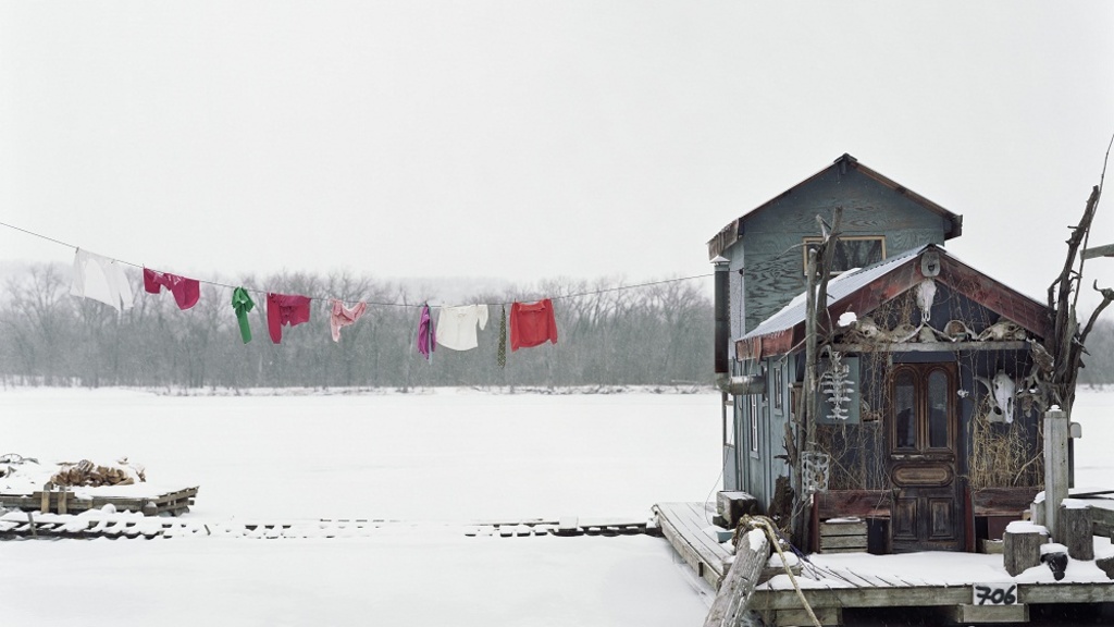 A photograph of a houseboat and a clothesline on the Mississippi River in the winter.