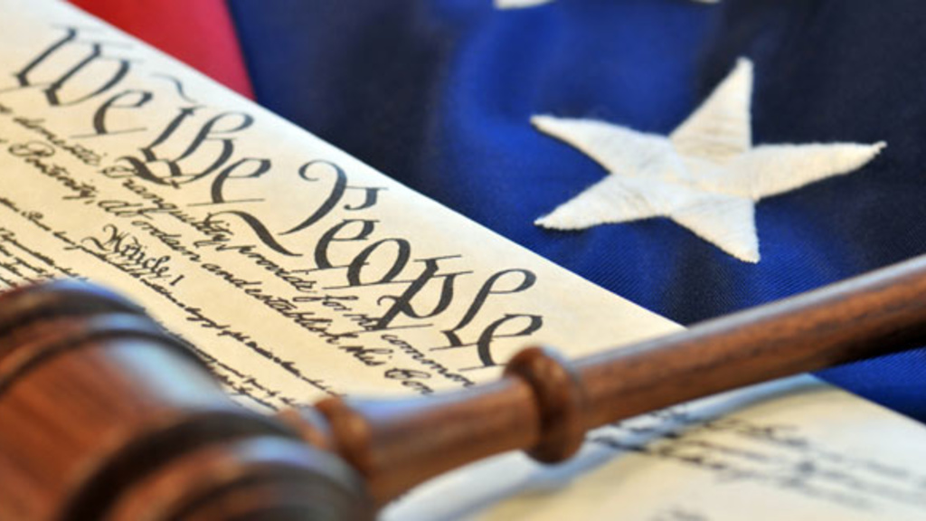 Color photo of a gavel, U.S. Constitution, and American flag