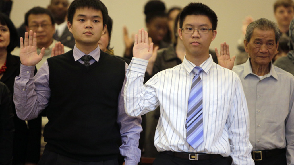 George Chen (left) from Taiwan and his brother Henry Chen stand and place their hands as they swear the Oath of Allegiance to the United States during a naturalization ceremony at the Federal Courthouse for the Northern District of Iowa on Nov. 16, 2012, 