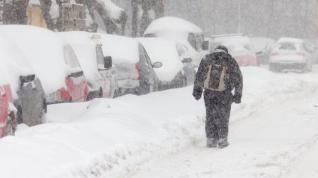 Winter weather photo of student truding along a street during a blizzard