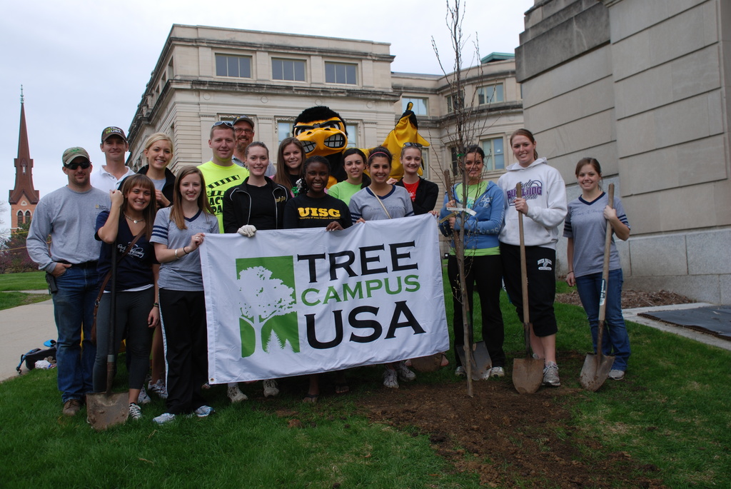 students, staff pose with Herky and the Tree Campus banner