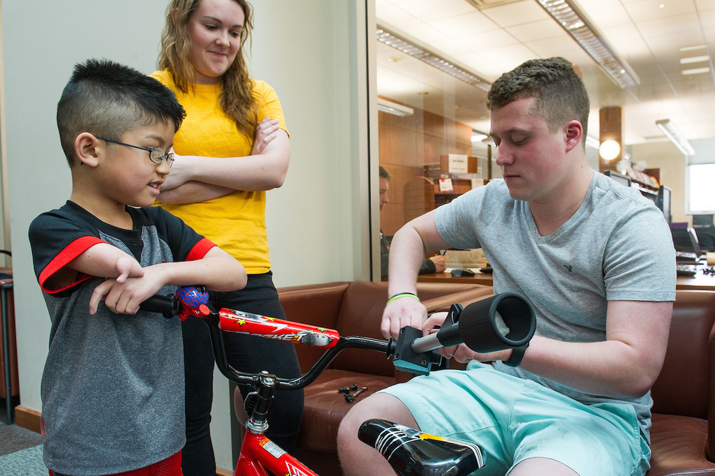 engineering students prepare an assistive device for a boy&#039;s bicycle