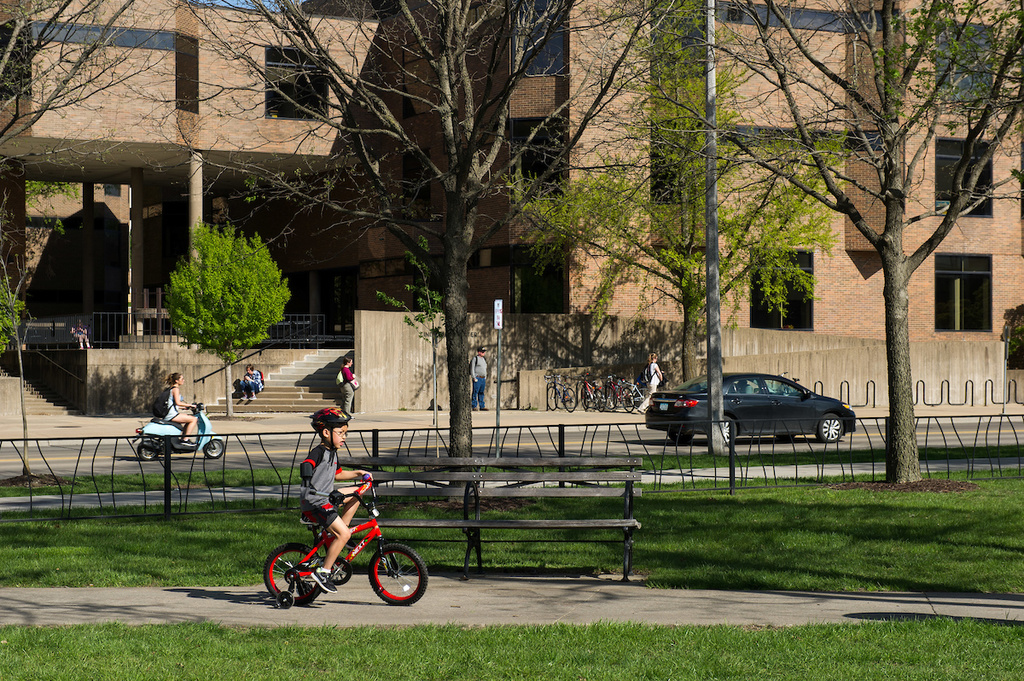 boy riding bicycle on campus using assistive device