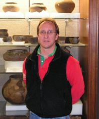 A man standing in front of a display of pottery
