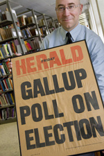 man in UI library holding Herold Gallup Pool on Election poster