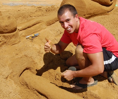 Delta Sigma Delta member Brad Adams gives thumbs up as he works on the fraternity's sculture for Sand in the City