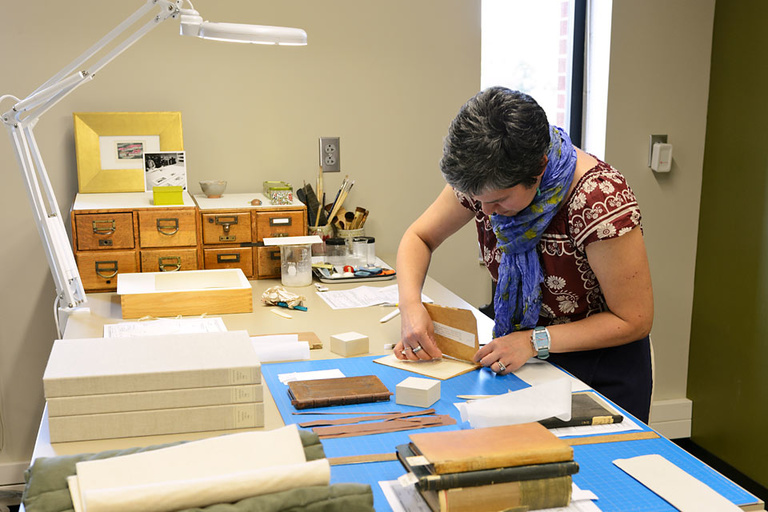 conservator, Giselle Simon works to repair a rare book