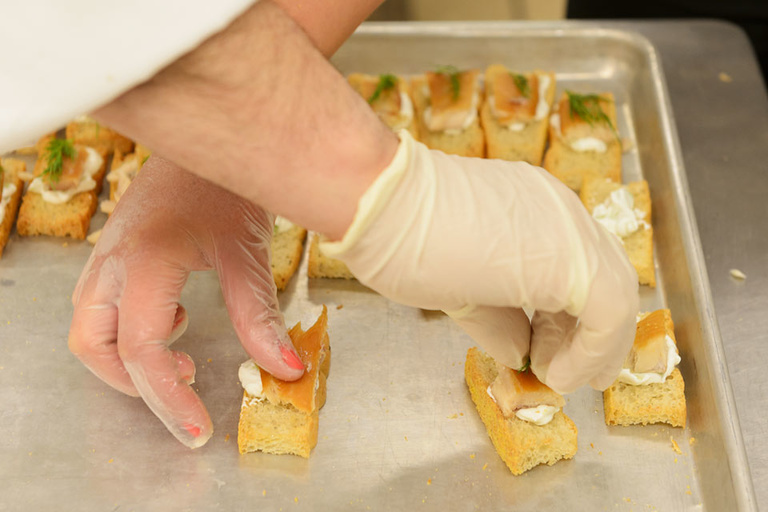 Hands arranging canapes on a tray.