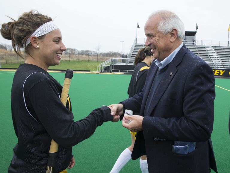FIH President Leandro Negre presents an FIH pin to Natalie Cafone during their practice Wednesday, April 23, 2014 at Grant Field on the UI campus in Iowa City.