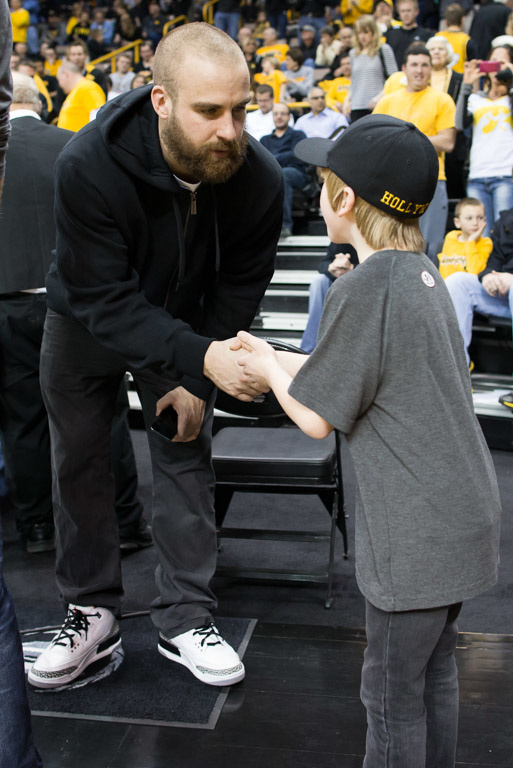 An adult male and young boy shake hands.