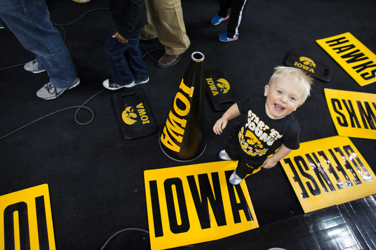 A young boy stands on an IOWA cheer card.